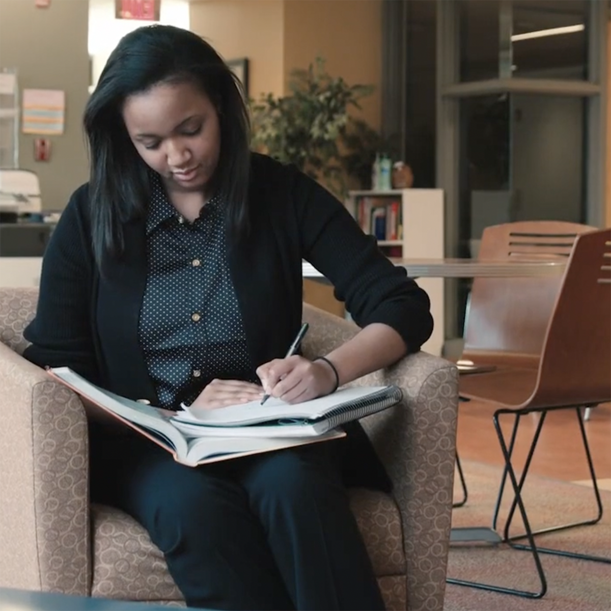 Photo of a student writing in a notebook in her lap