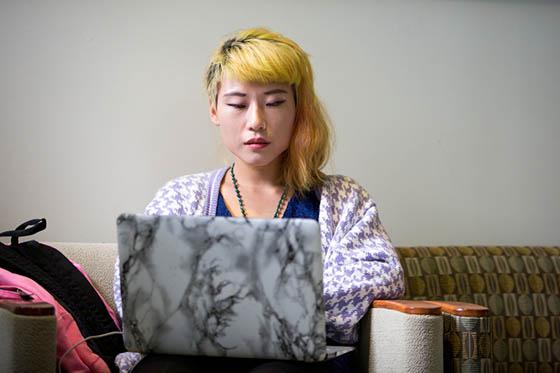 Photo of a student working on her laptop, sitting on a couch