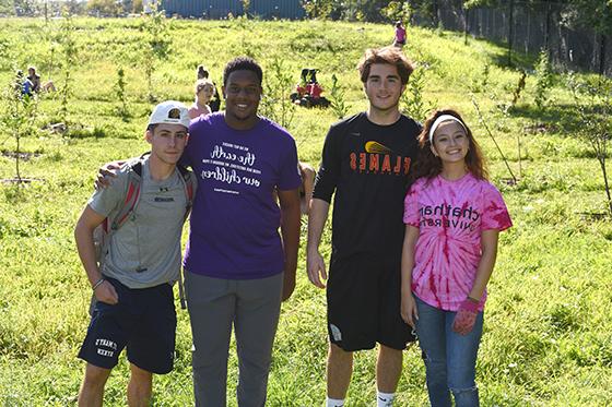 Photo of four Chatham University students posing with arms wrapped around each other at Eden Hall Farm. 